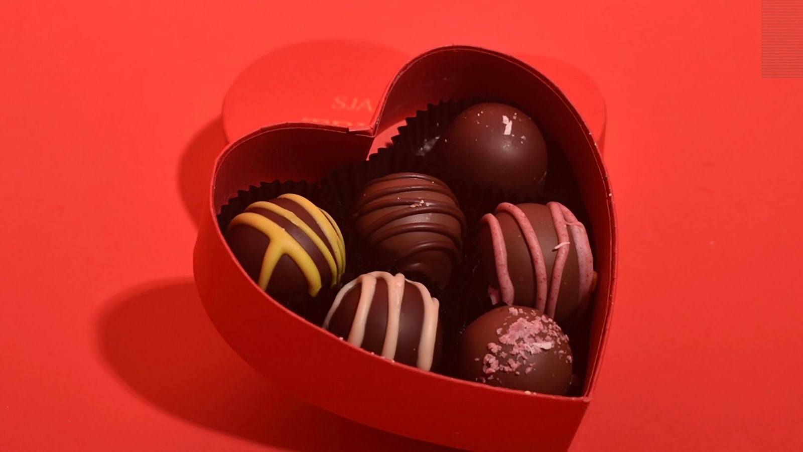 Heart-shaped red gift box filled with assorted chocolate truffles